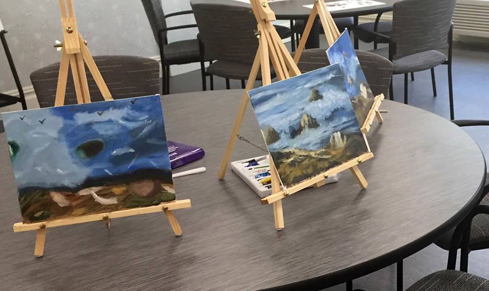 Paintings sit on small tabletop easels in the Art Studio at The Ambassador