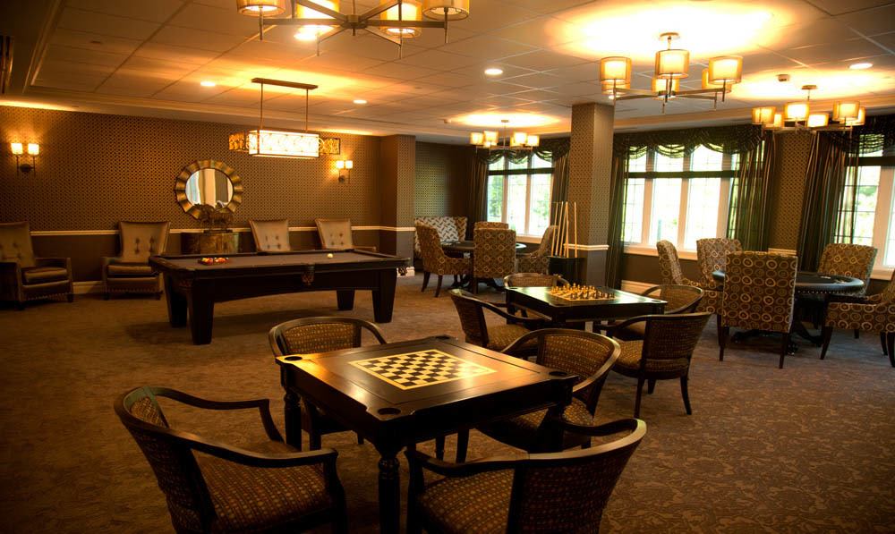 Chesse tables, a pool tables and cues set amongst comfortable chairs and tables in the Club Room at The Ambassador