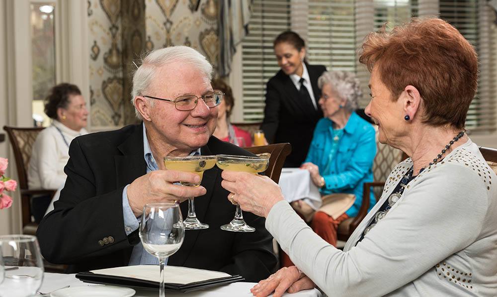 Lady and gentleman enjoying drinks at a table in the Heathcote Dining Room at The Ambassador