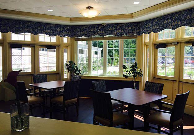 Tables by the windows overlooking the garden by the Five Corners Bistro at The Ambassador
