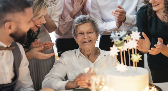 elderly lady blowing out candles of her cake