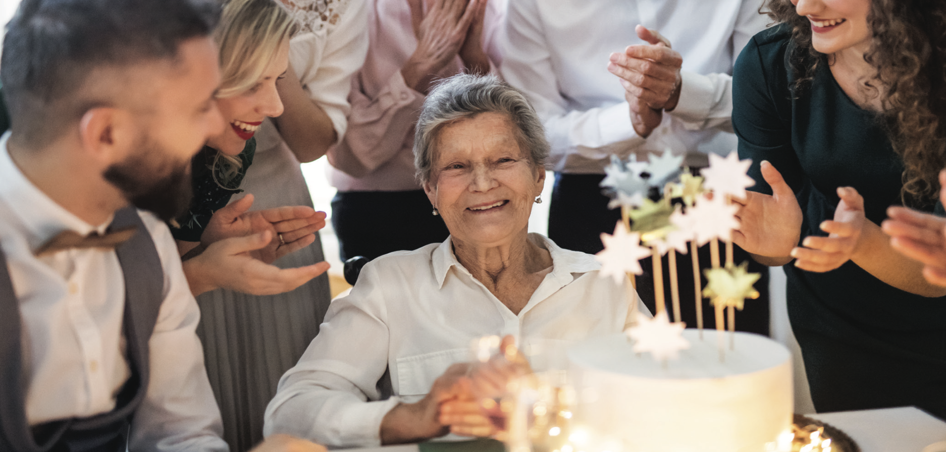 elderly lady blowing out candles of her cake